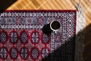 فرش ماشینی قرمز با حاشیه طرحدار روی پارکت